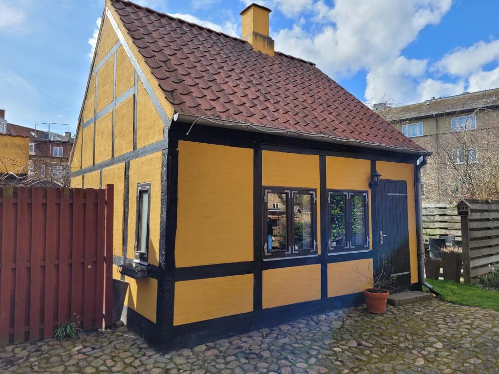 une petite maison jaune avec un toit brun dans l'établissement Oasen Holbæk Centrum, à Holbæk