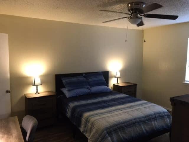 een slaapkamer met een bed met 2 nachtkastjes en 2 lampen bij Simple 1-bedroom unit upstairs close to Fort Sill! in Lawton