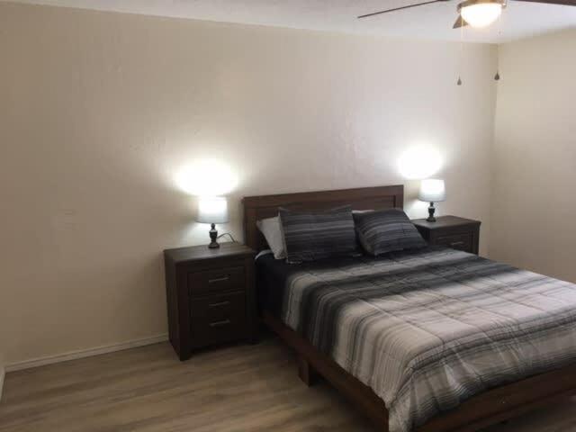 ein Schlafzimmer mit einem Bett und zwei Nachttischen mit Lampen in der Unterkunft Cozy Upstairs 1 Bedroom Apartment close to Fort Sill in Lawton
