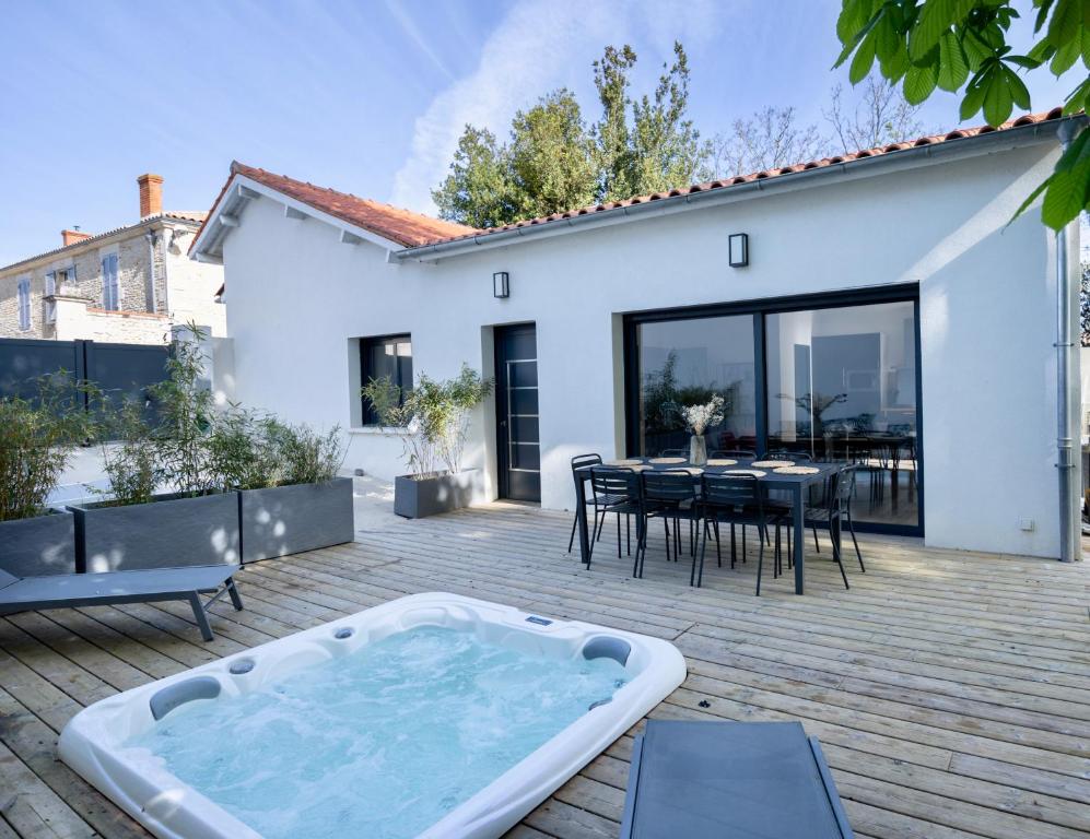 - un bain à remous sur une terrasse avec une table et des chaises dans l'établissement Maison T4 Climatisée avec Jacuzzi à Lagord, à Lagord