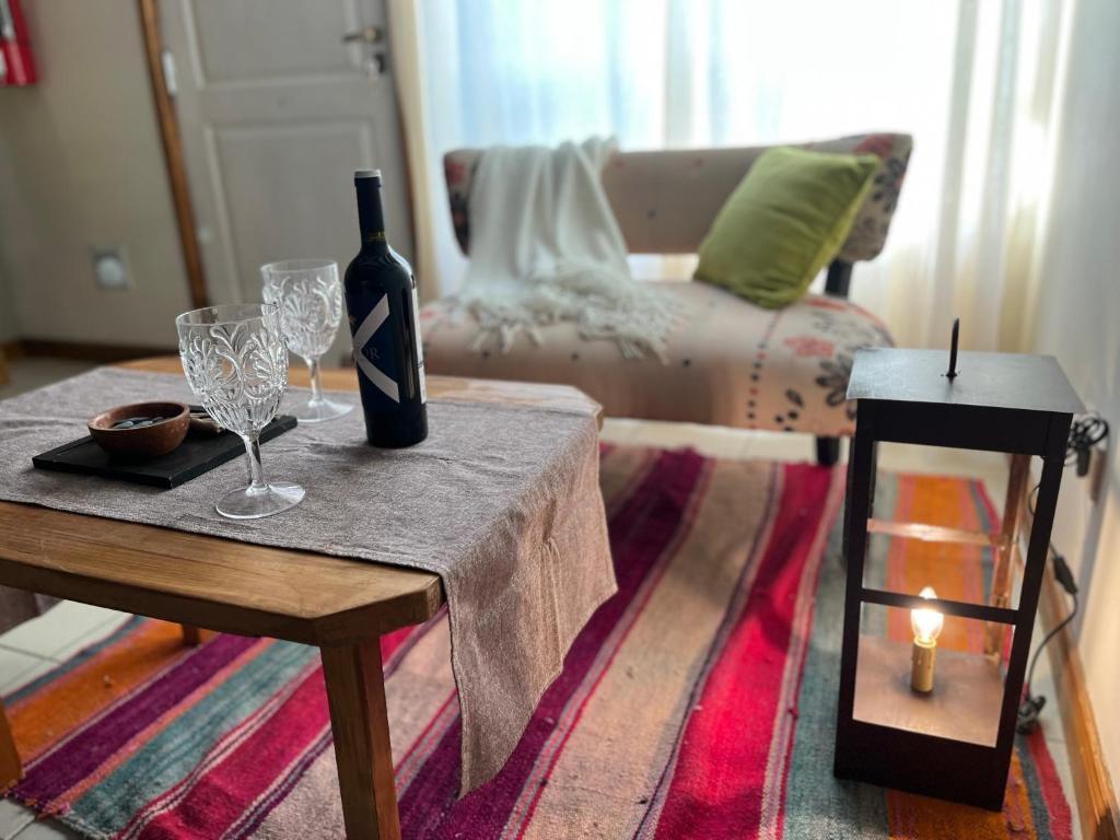 um quarto com uma mesa com uma garrafa de vinho e copos em Narcisos y Amapolas en Ushuaia em Ushuaia