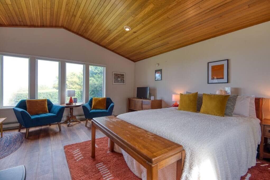 a bedroom with a large bed with a wooden ceiling at #StayinMyDistrict Cape Arago Ocean Studio Suite in Coos Bay