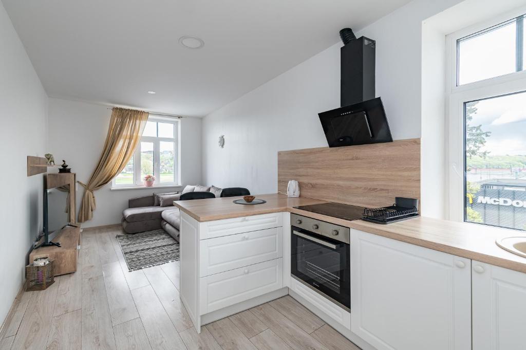 a kitchen with white cabinets and a living room at Serene Nemunas River View apartment near McDonald by Polo Apartments in Kaunas