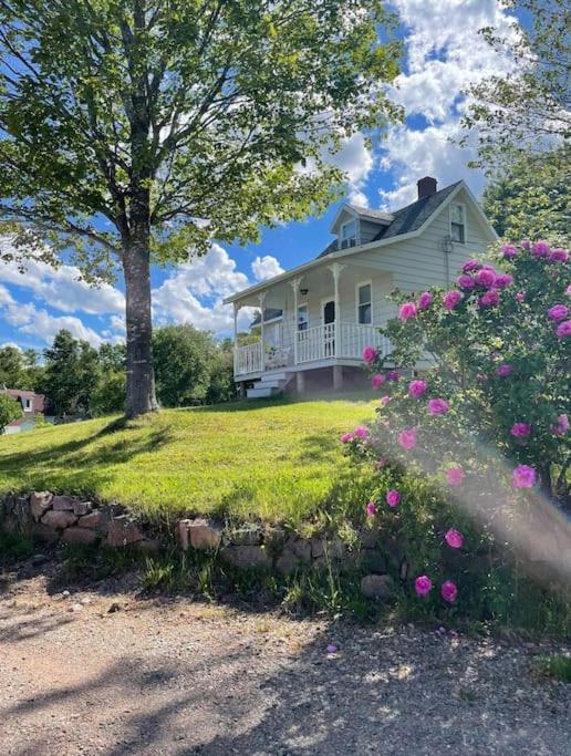 a white house with pink flowers in front of it at Ardan Cottage in Ingonish in Ingonish Beach