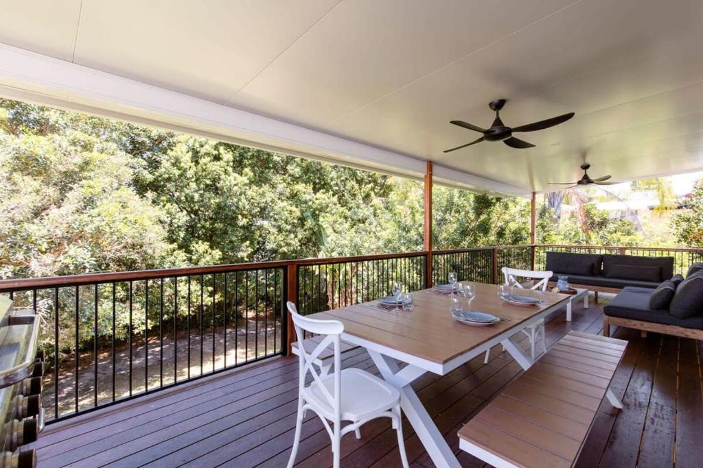 a wooden deck with a table and a ceiling fan at Charming Coastal Cottage in Caloundra