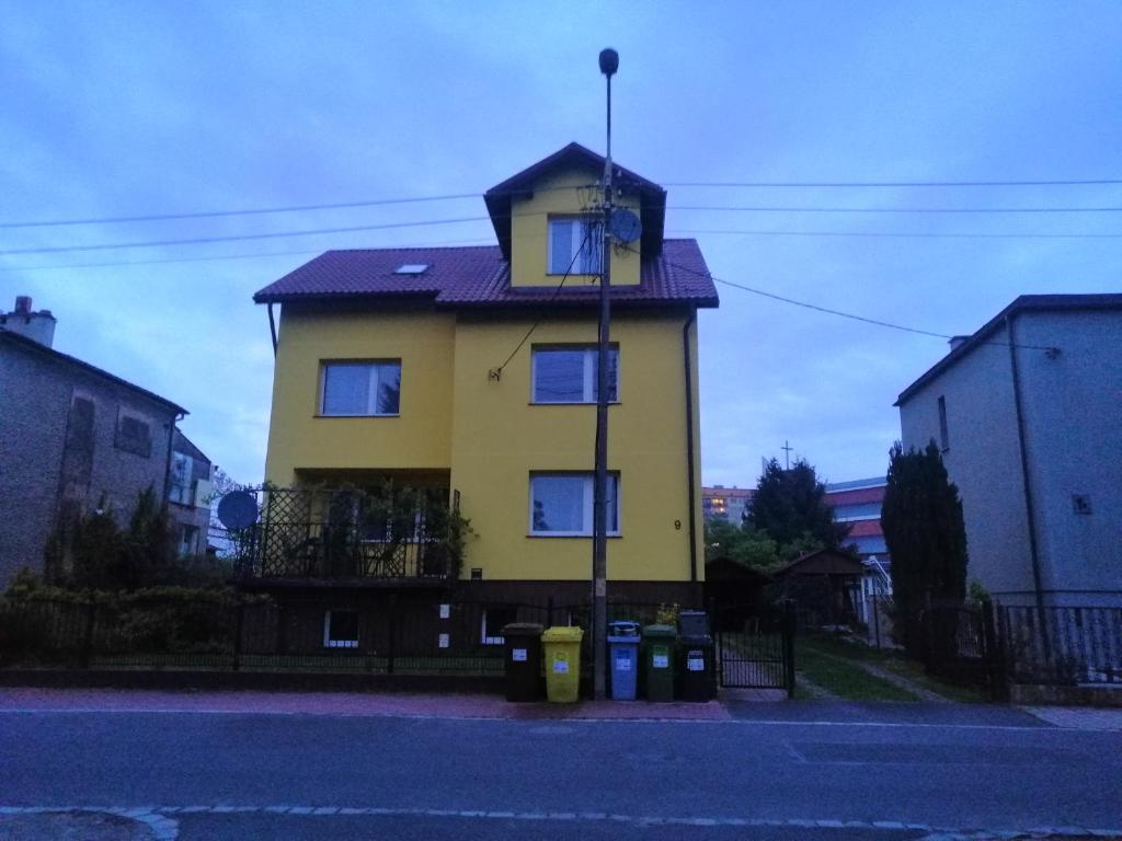 a yellow house with blue windows on a street at Willa Malbork in Wrocław