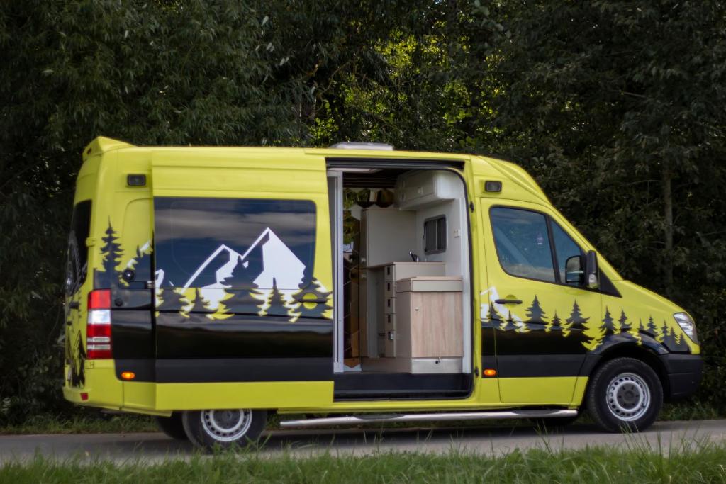 a yellow van with trees and mountains painted on it at Camper On Road Tenerife in Los Cristianos