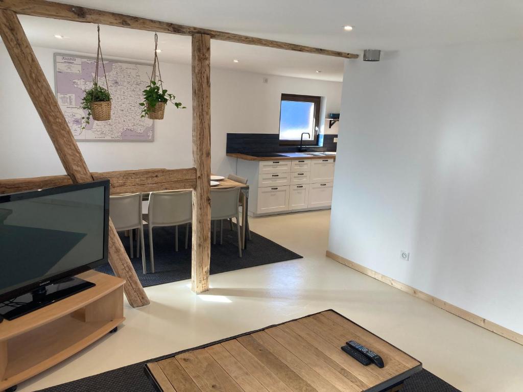 ein Wohnzimmer mit einem TV und einer Küche in der Unterkunft L’atelier du bricoleur in Marckolsheim