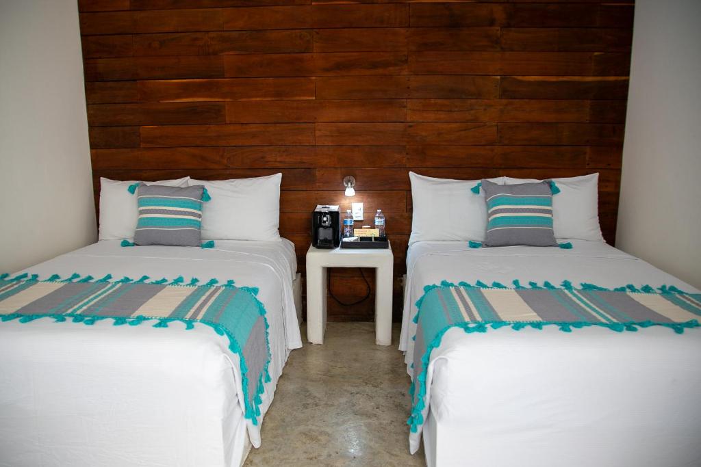 um quarto com duas camas e uma mesa com um telefone em Hotel Boutique Villa Balu em Bacalar