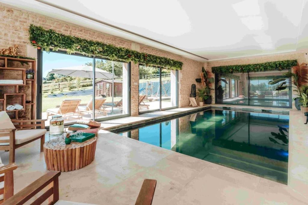 a swimming pool in a house with a living room at Superbe Villa avec piscine intérieure chauffée in Bonneville-sur-Touques