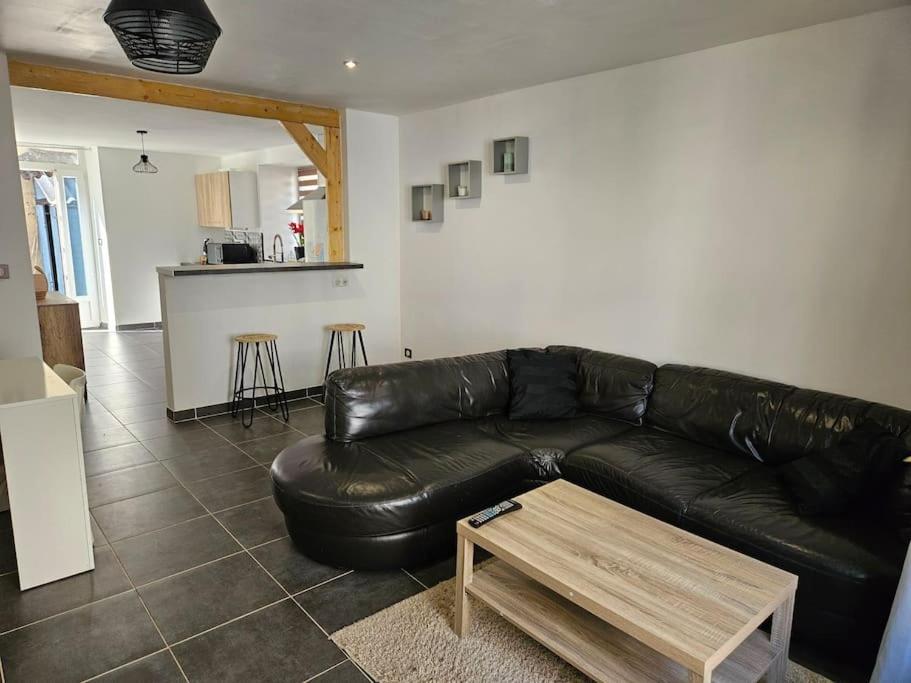 un canapé en cuir noir dans un salon avec une table dans l'établissement Le centre-ville du Berry, à Châteauroux