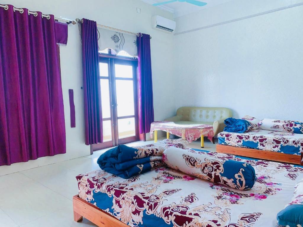 Zimmer mit 3 Betten und einem Fenster mit lila Vorhängen in der Unterkunft Lake View Ninh Binh in Tam Ðiệp