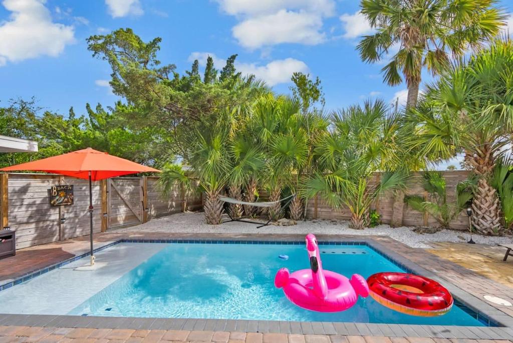a swimming pool with a pink inflatable raft and an umbrella at Heated Pool by the Sea Mini Golf Dogs OK in Saint Augustine