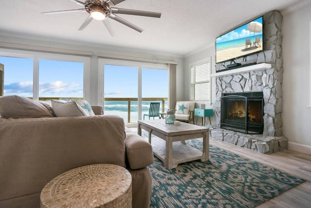 a living room with a couch and a fireplace at Spectacular Oceanfront! Blissful Balconies + BBQ in Saint Augustine