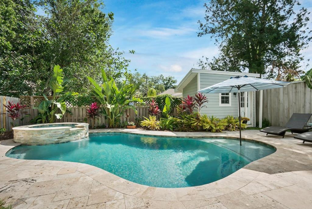- une piscine avec un parasol dans l'arrière-cour dans l'établissement Charming Cottage w Pool, Walkable to Downtown, à Saint Augustine