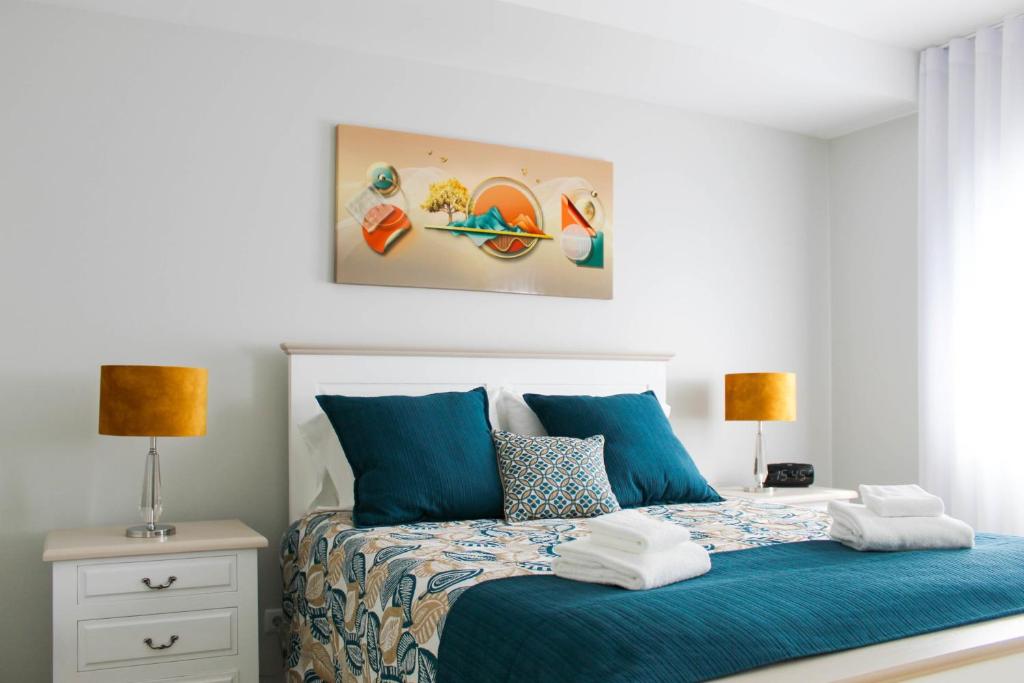una camera da letto con un letto con lenzuola blu e due lampade di Dreamscape Villa a Ponta Delgada