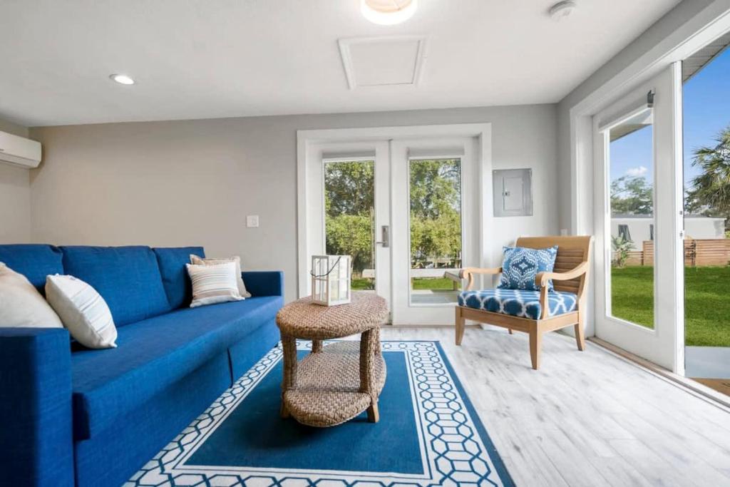 sala de estar con sofá azul y silla en Coral Cottage, Stylish Studio Suite on Canal, Walkable to Beach, Private Parking, en St. Augustine