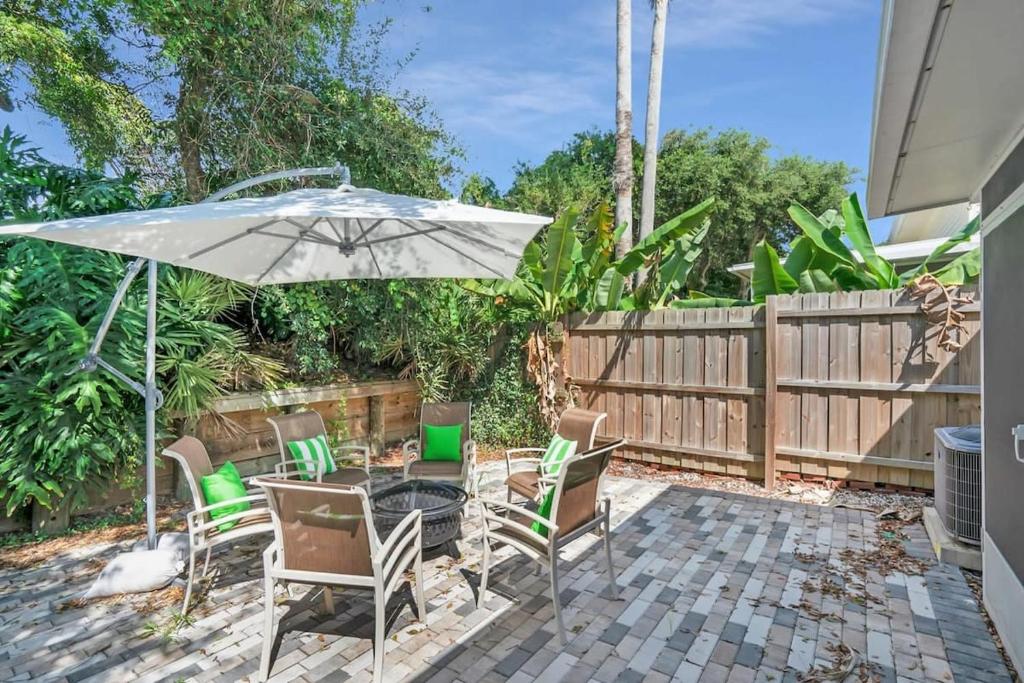 eine Terrasse mit einem Tisch, Stühlen und einem Sonnenschirm in der Unterkunft Sapphire Skies! Sweet Beach Condo Steps from the Sand and Surf in St. Augustine