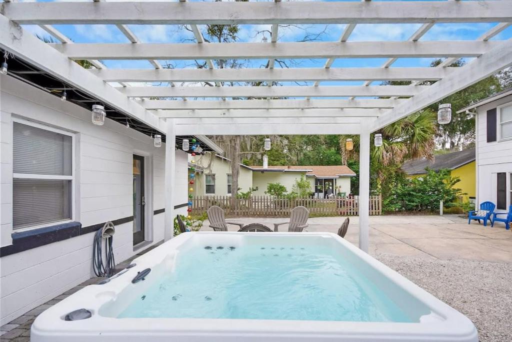 a hot tub on a patio with a pergola at Uptown Treasure with Spa Dogs Ok Dreamy Patio in St. Augustine