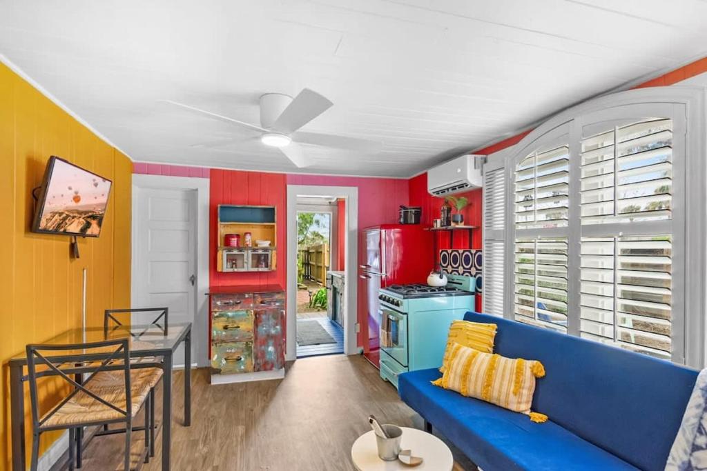 a living room with a blue couch and a kitchen at Marvelous Mermaid Bungalow, Dog-Friendly Downstairs Apt in Prime Vilano Beach in Saint Augustine