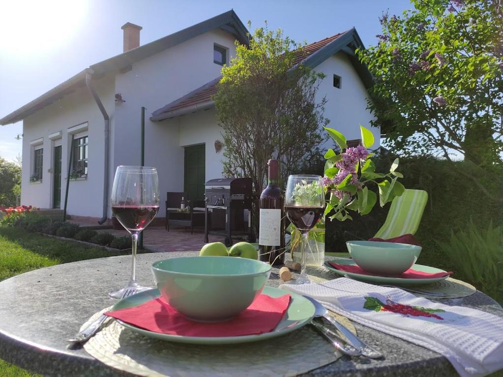 una mesa con un plato de comida y una copa de vino en Szőlőhegyi házikó - Cottage in the vineyard en Balatonszemes