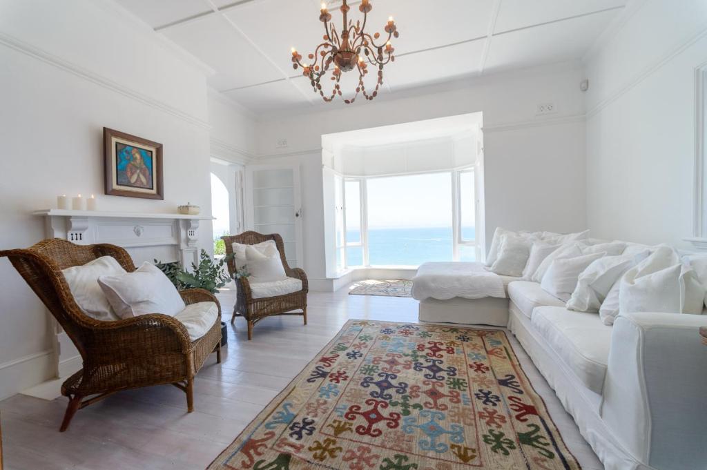 sala de estar con sofá blanco y lámpara de araña en Kalimera Beach House, en Mossel Bay