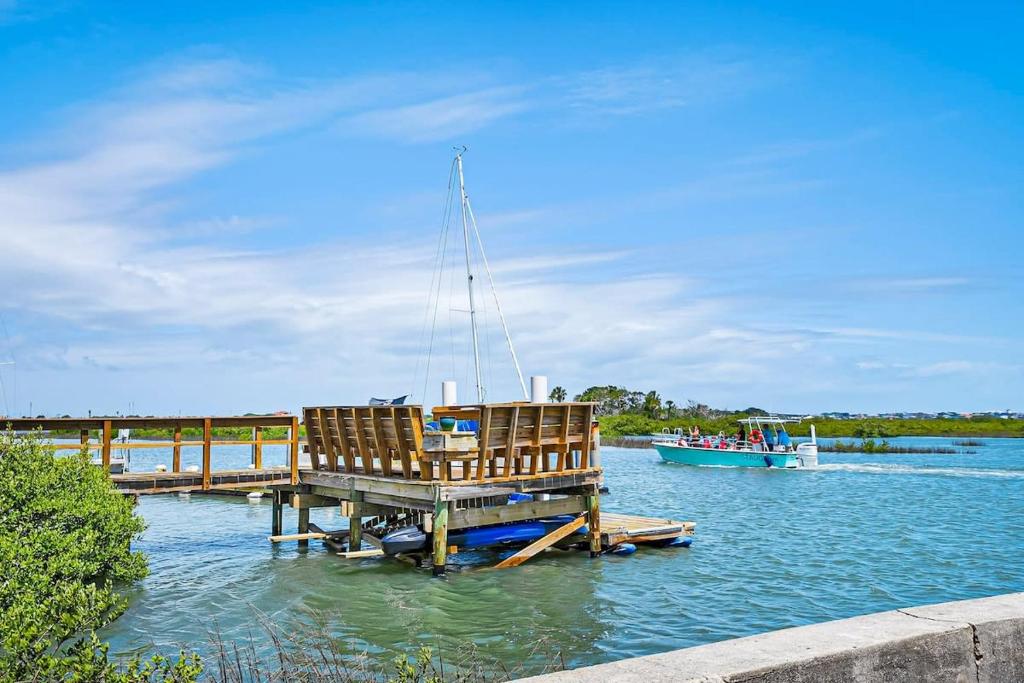 a dock with a chair and a boat in the water at New Private Apt in Uptown St Aug Walk Everywhere in Saint Augustine