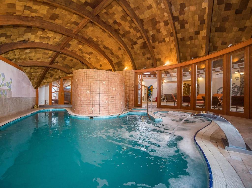 een binnenzwembad met een glijbaan in een gebouw bij Hotel Piroska in Bük