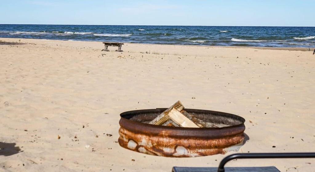 a tub on a beach with the ocean in the background at Beach Club of Oscoda Captains Watch on the Lake in Oscoda