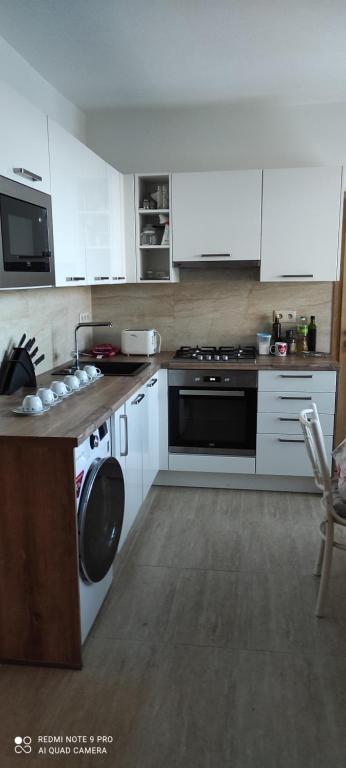 uma cozinha com armários brancos, um fogão e uma máquina de lavar louça em Apartmán Sofia em Levice