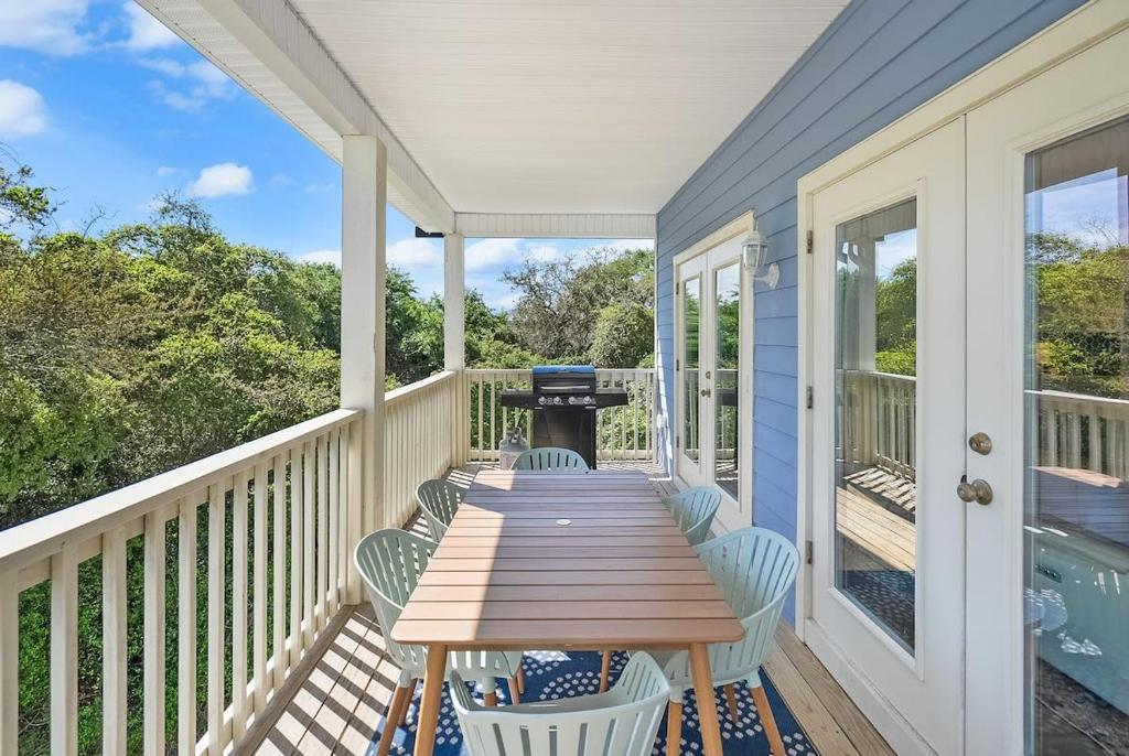 a wooden table on a porch with chairs and a grill at Treetop Terrace 250 Steps to Beach Heated Swim Spa in Saint Augustine
