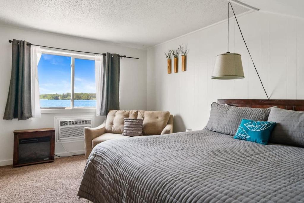 a bedroom with a bed and a chair and a window at Fife Lake Lodge Multi-Level Lake View King Suite in Fife Lake