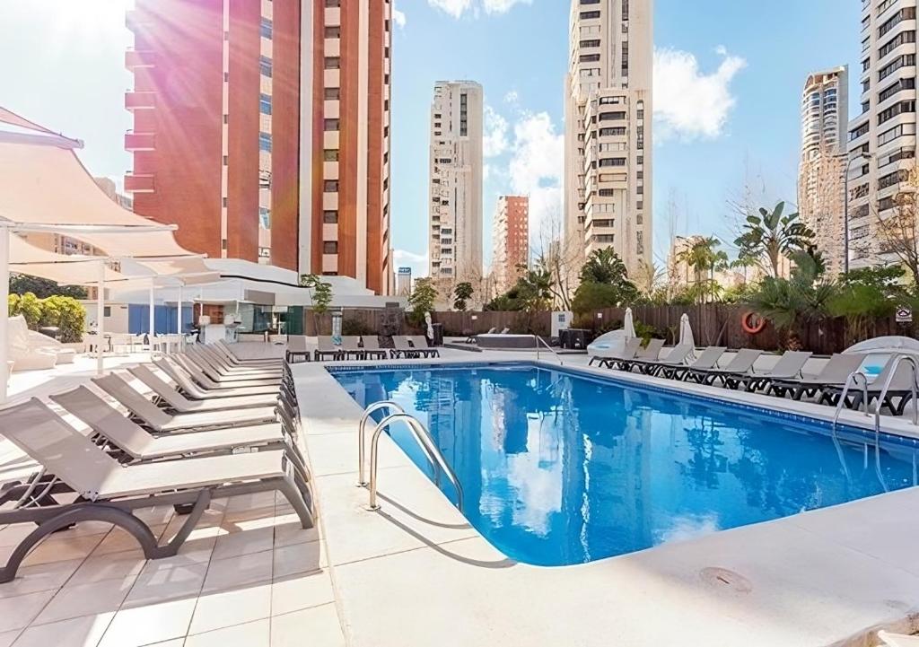 a swimming pool with chaise lounge chairs next to a building at Flamingo Beach Resort - Adults Recommended in Benidorm