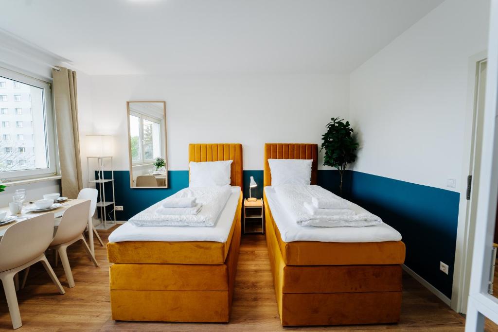 two beds in a room with a table and chairs at Jenapartments for4 Boxspring & Smart TV & Waschmaschine in Jena