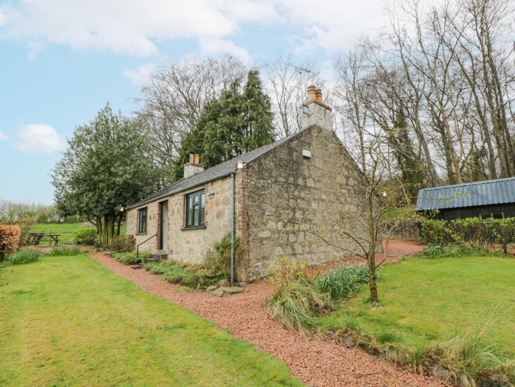 an old stone building with a chimney on top at Beechgrove Cottage - Pitmedden Gardens in Ellon