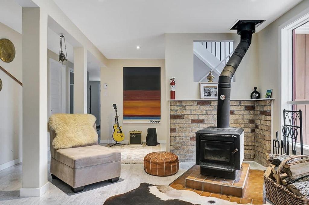 a living room with a wood stove and a chair at La Hacienda - Edelweiss après-ski - wooded escape in Val des Monts