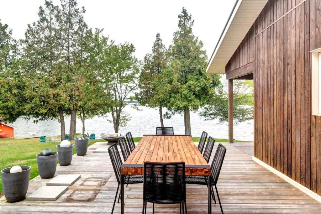 une table et des chaises en bois sur une terrasse à côté de l'eau dans l'établissement Stunning waterfront escape with European flair, à Delta