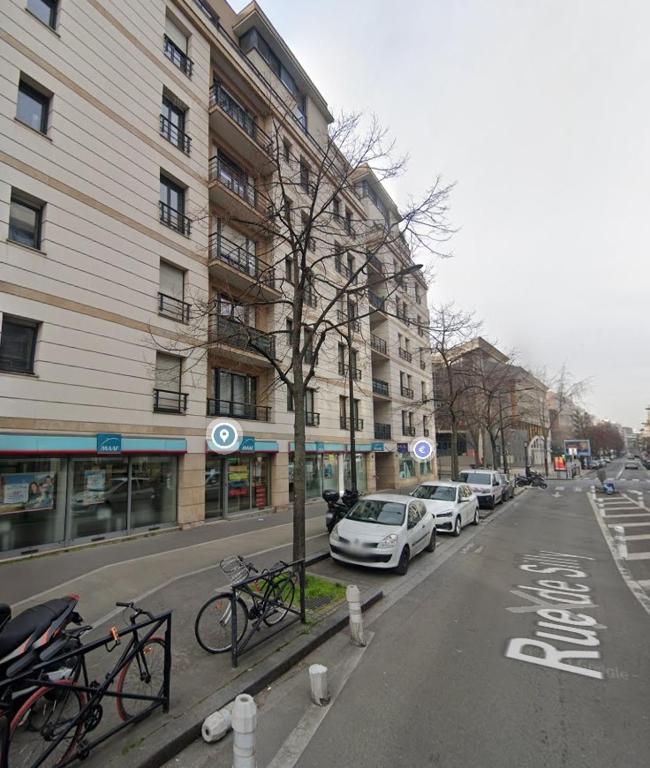 une rue avec des voitures garées sur le côté d'un bâtiment dans l'établissement Studio avec parking privé et métro, à Boulogne-Billancourt