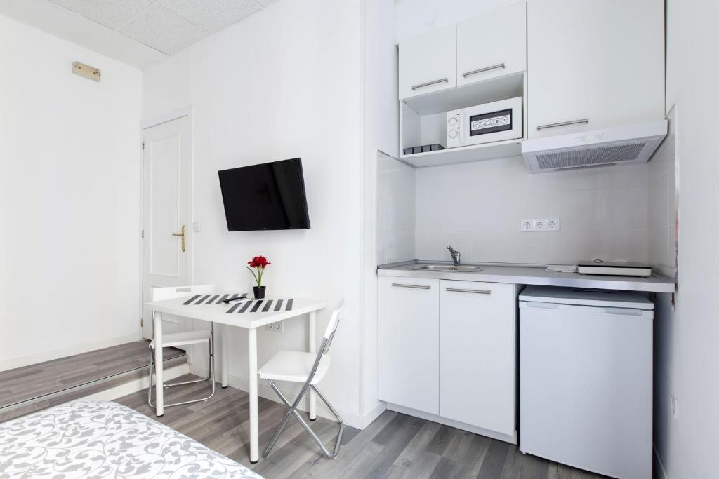 a small white kitchen with a desk and a bed at Gilbert accommodations in London