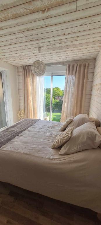 une chambre avec un grand lit avec une grande fenêtre dans l'établissement Le Cocon de Mina, 15 min du Puy du Fou, à Mortagne-sur-Sèvre