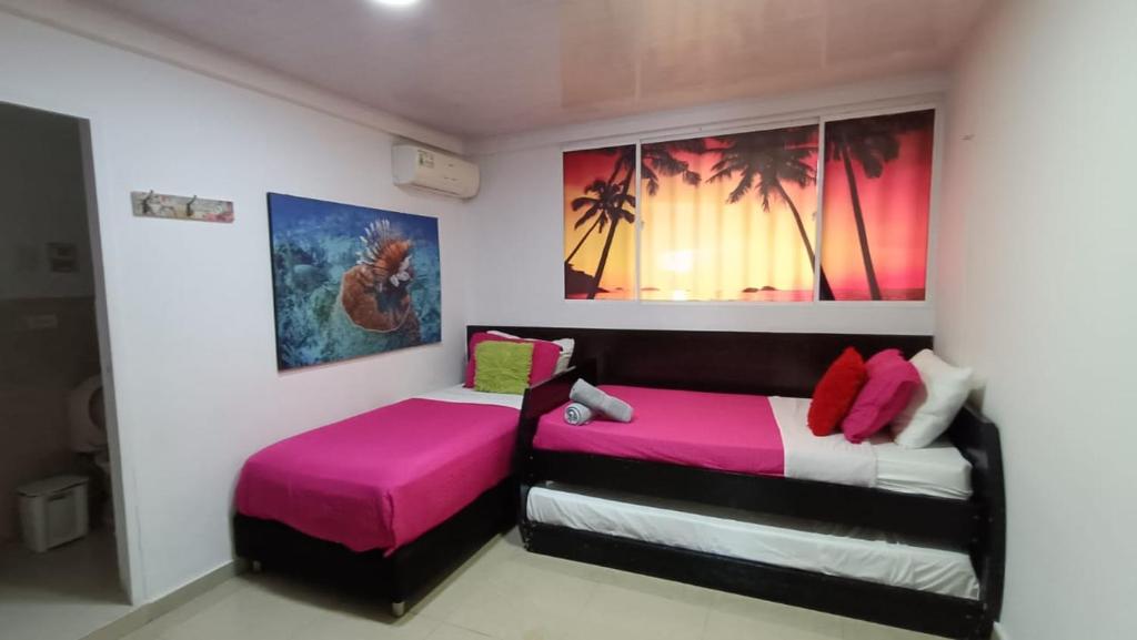 2 camas en una habitación de color rosa y negro en Jackuri Casa Hospedaje, en San Andrés