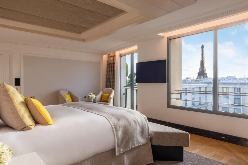 Schlafzimmer mit einem großen Bett und Blick auf den Eiffelturm in der Unterkunft Hotel du Collectionneur in Paris