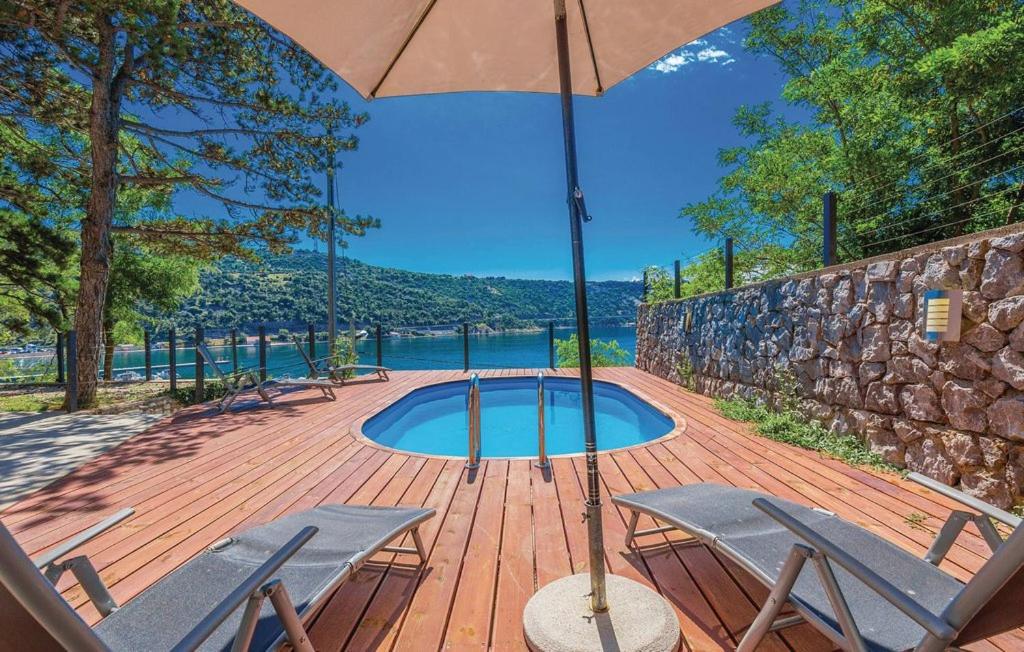 un patio con sombrilla, 2 sillas y una piscina en Villa Fortuna, en Bakarac
