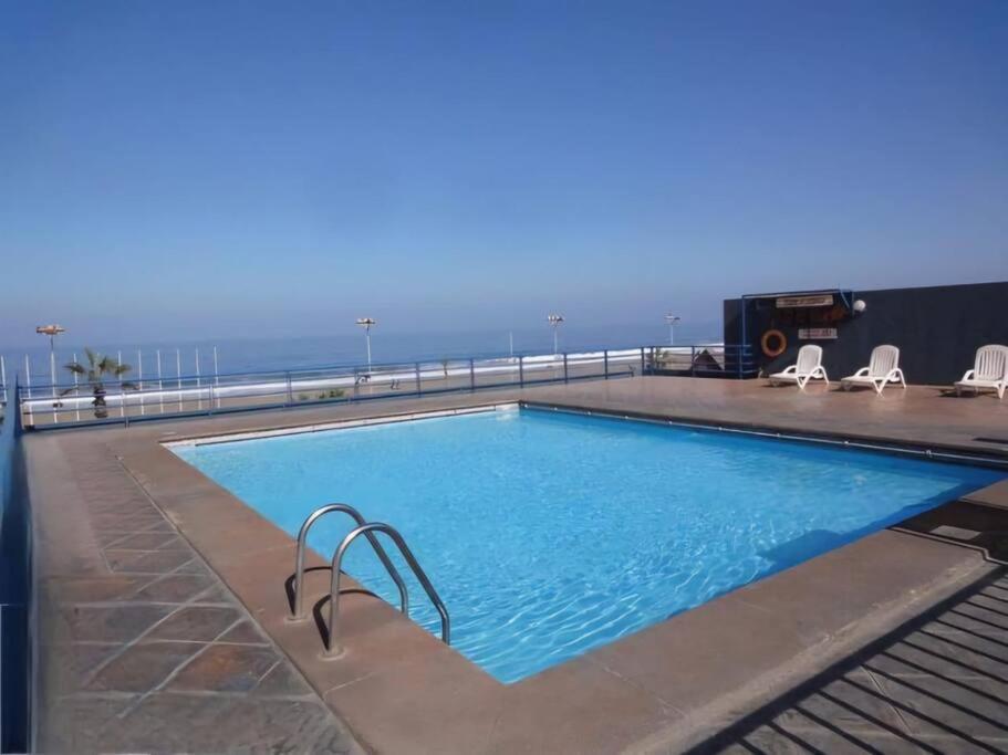 a swimming pool with the ocean in the background at Paraíso frente al mar en Iquique in Iquique