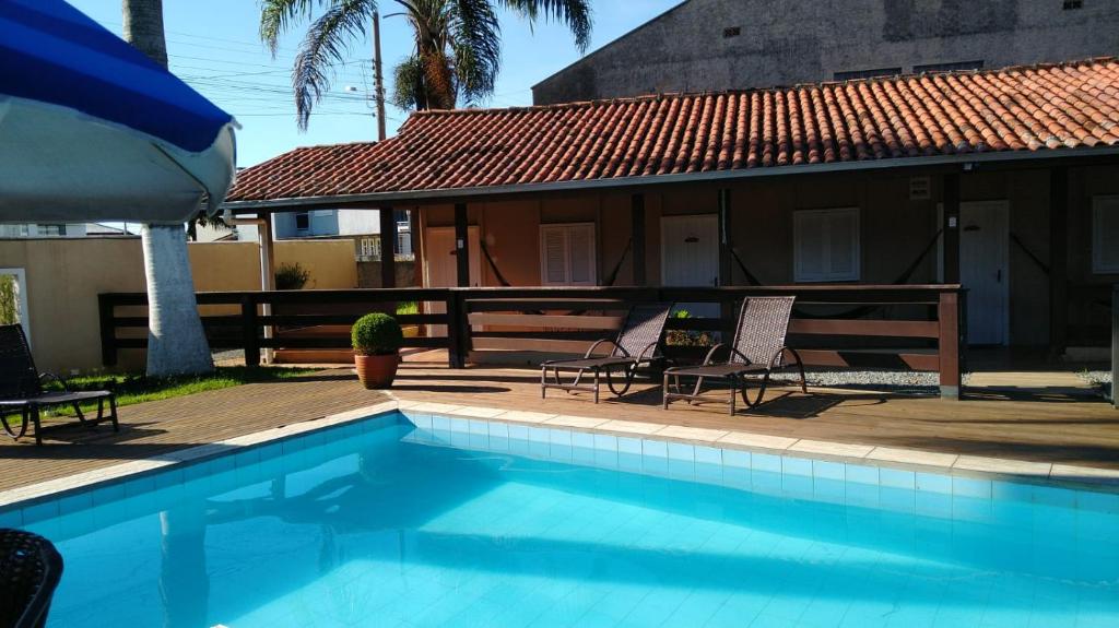 a swimming pool with two chairs and a house at Pousada Doce Vida in Marechal Luz