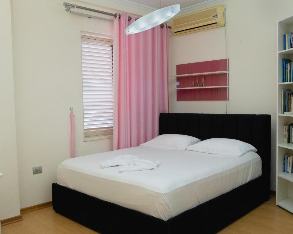 地拉那的住宿－Albjona Guesthouse 1，一间卧室配有一张带粉红色窗帘的床