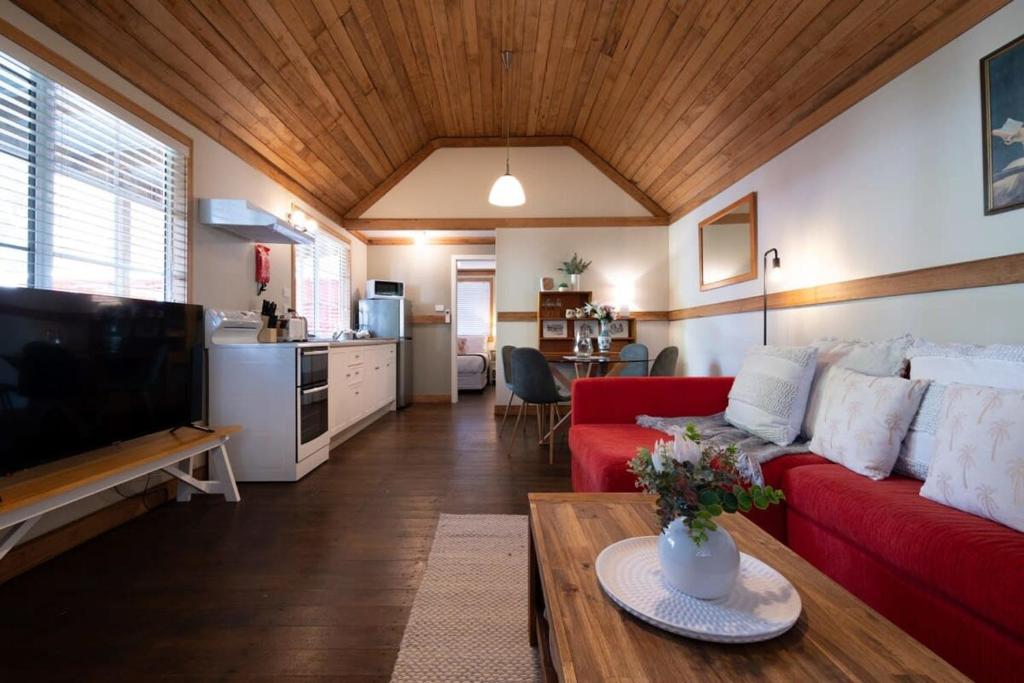 sala de estar con sofá rojo y mesa en Station Cottage, en Kings Park