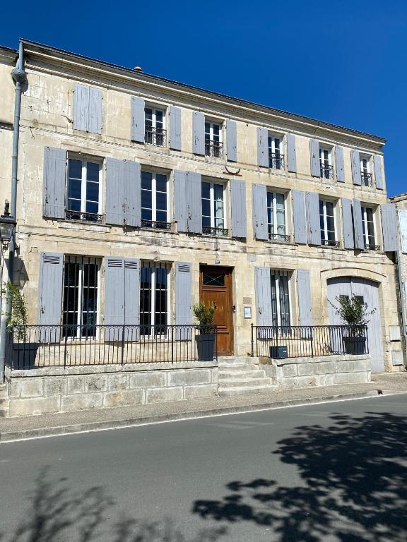 a large stone building with windows and a wooden door at Le Clos des Grands Frênes in Pons