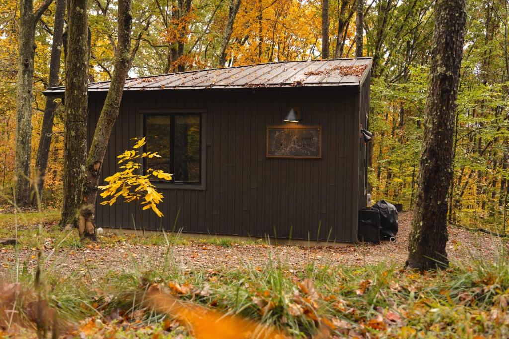 uma cabana negra na floresta com árvores em Hot Tub Fire Pit Grill - 10 Mins To Ash Cave em Stella