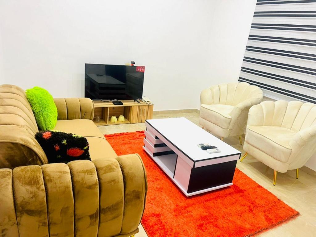 a living room with a couch and two chairs and a tv at COMPLEXE HOTELIER LA BONTE ( CHB ) in Abomey-Calavi